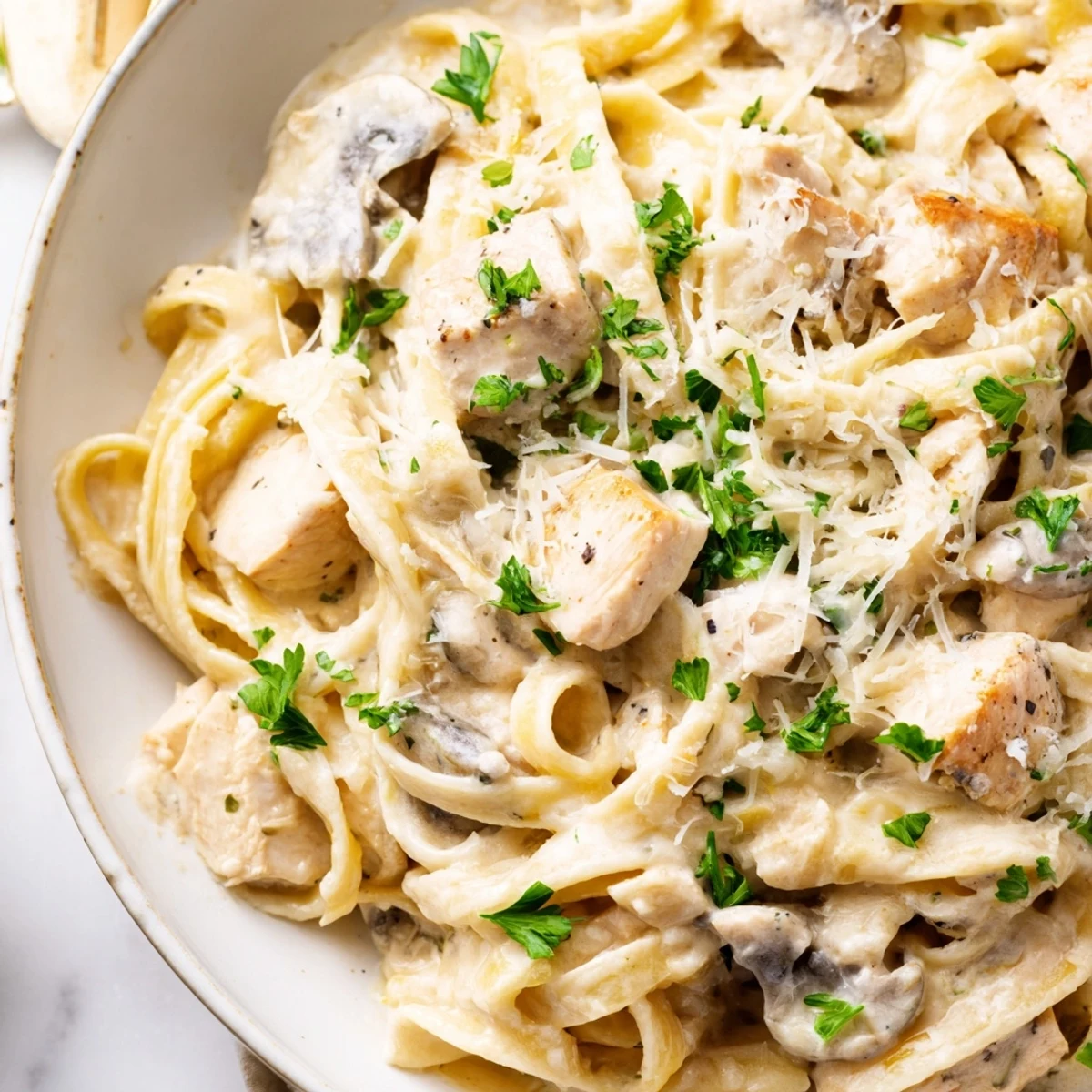A close-up of a cheesy Chicken Fettuccine Alfredo Bake with parsley, smelling wonderfully aromatic.