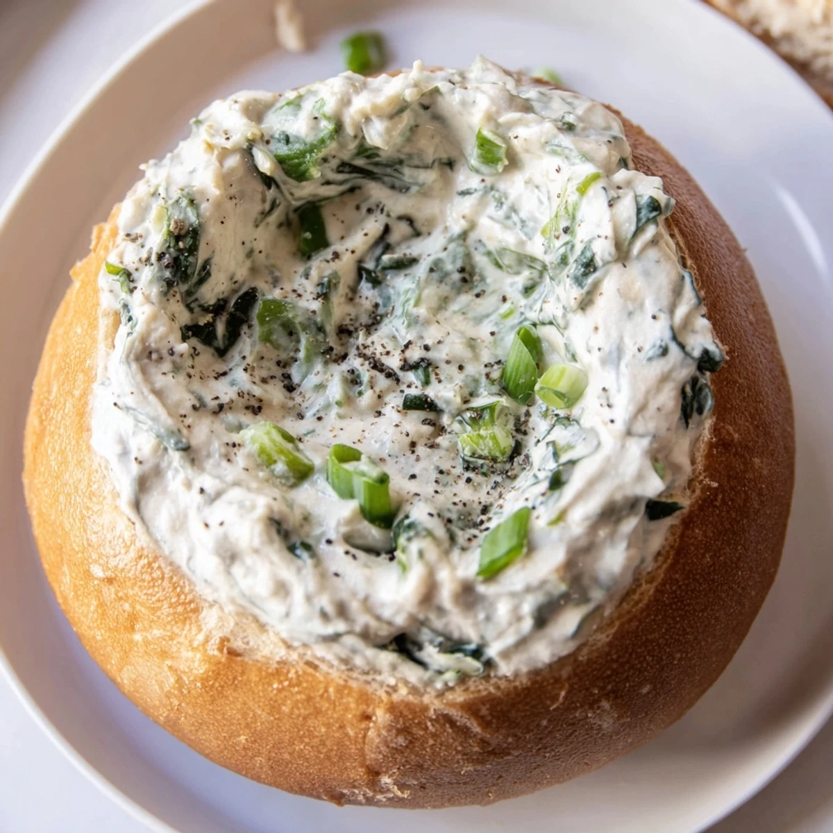 A golden-brown bread bowl overflows with creamy, homemade spinach dip, ready for dipping.