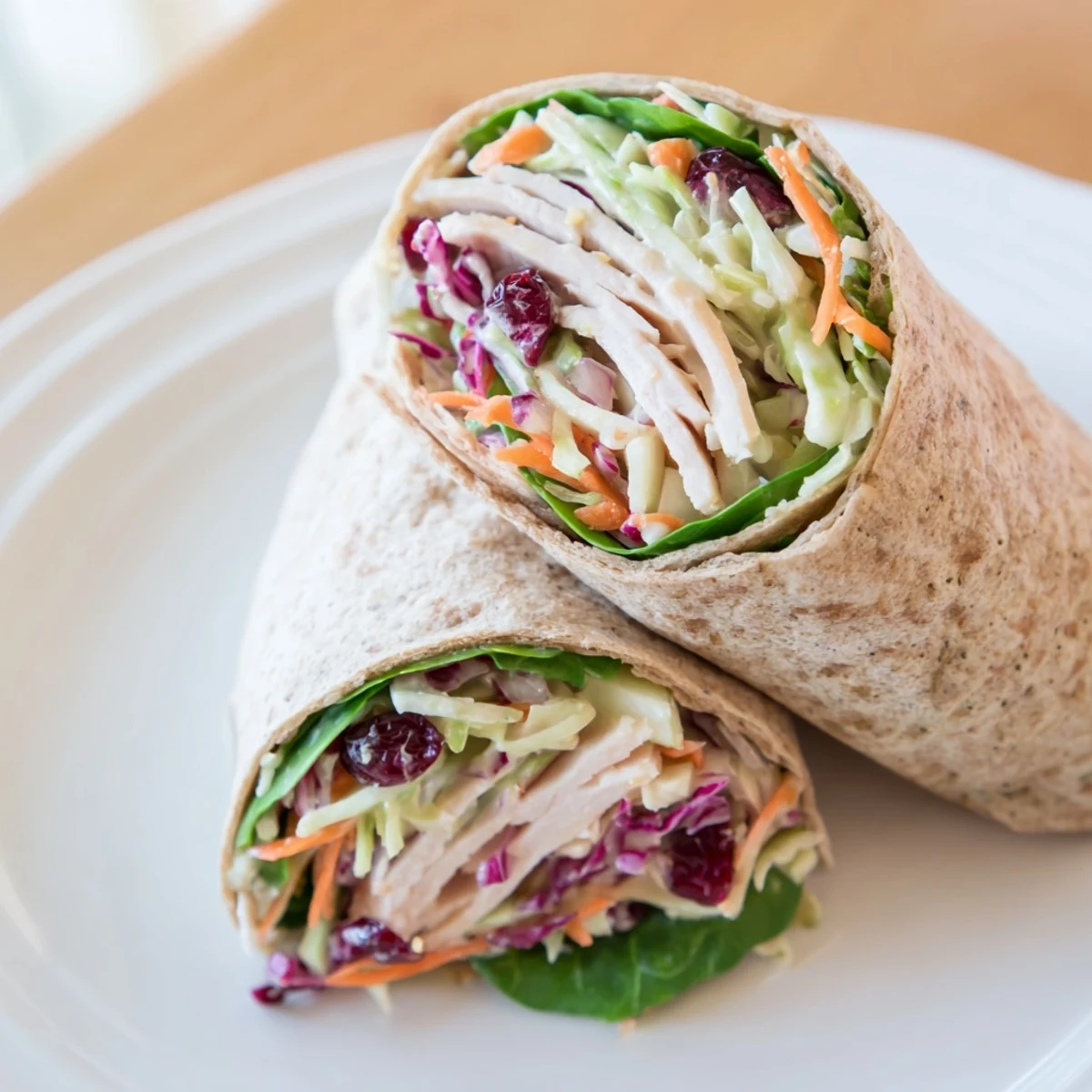 Wrapped in whole wheat, a delicious view of Cranberry Apple Slaw Turkey Wraps served with baby spinach.