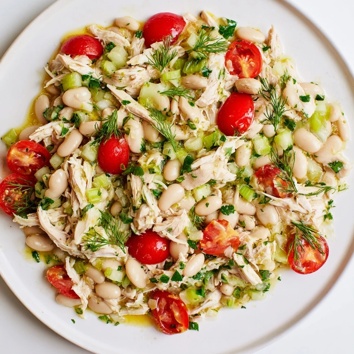 Bright bowl of Lemony White Bean Chicken Salad with cherry tomatoes, fresh parsley, and dill, served as a light, protein-packed main dish.