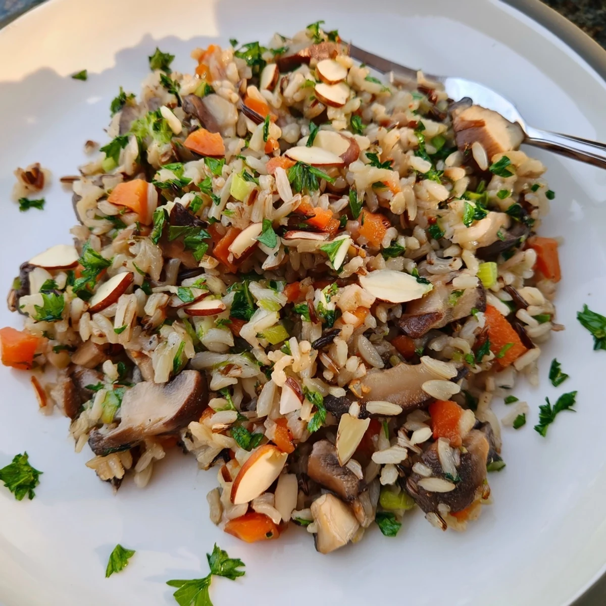 Steaming bowl of Wild Rice and Mushroom Pilaf garnished with fresh parsley and slivered almonds, showcasing its hearty texture and earthy sautéed mushrooms as a vegetarian side dish.