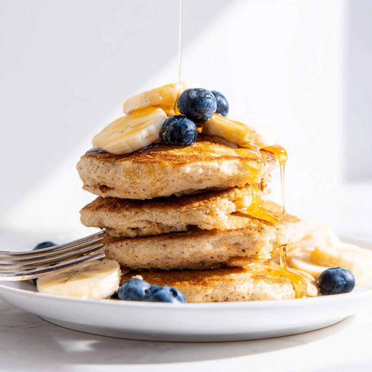 Golden-brown Protein Power Pancakes stacked high, topped with fresh berries and a drizzle of maple syrup on a rustic plate.  