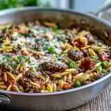 Spoonful of Comforting Ground Beef Orzo Dinner topped with Parmesan and parsley, served steaming in a rustic skillet.