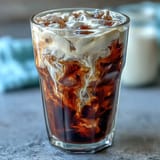Creamy vanilla sweet cream floats atop rich cold brew coffee, perfect for sipping.