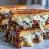 Close-up of a Philly Cheesesteak Grilled Cheese stuffed with steak and peppers.