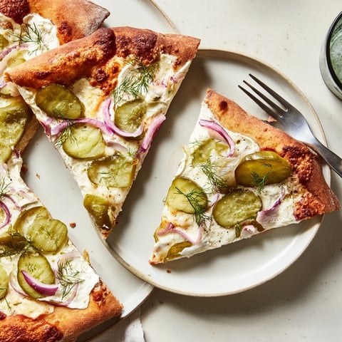 A deliciously unique Pickle Pizza with creamy sauce and crunchy dill toppings.  