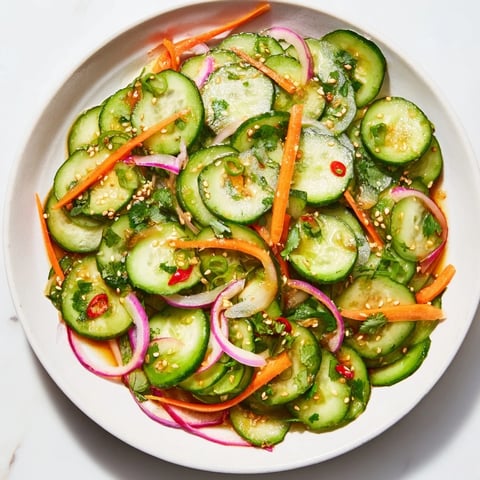 Refreshing cucumber salad remix with vibrant colors and Asian-inspired tangy dressing.  