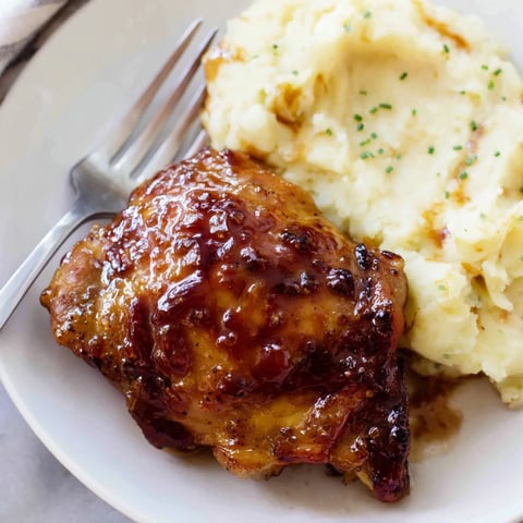 Succulent honey BBQ chicken thighs paired with creamy garlic mashed potatoes on a plate.  
