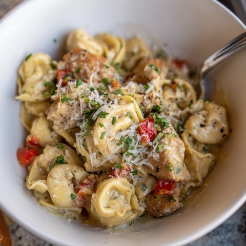 Zesty Cajun Garlic Parmesan Chicken Tortellini served with fresh parsley and extra cheese.  