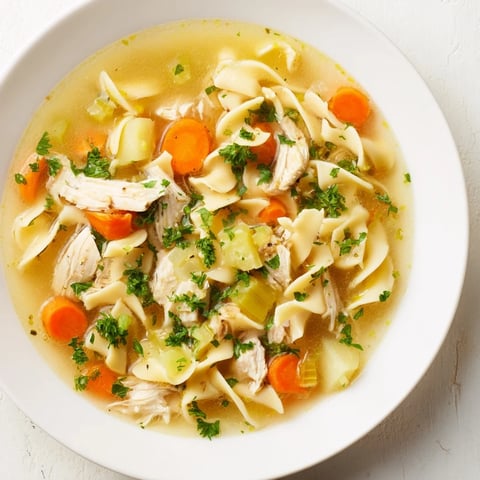 Homemade chicken noodle soup steaming in a bowl, showcasing tender chicken and vegetables.