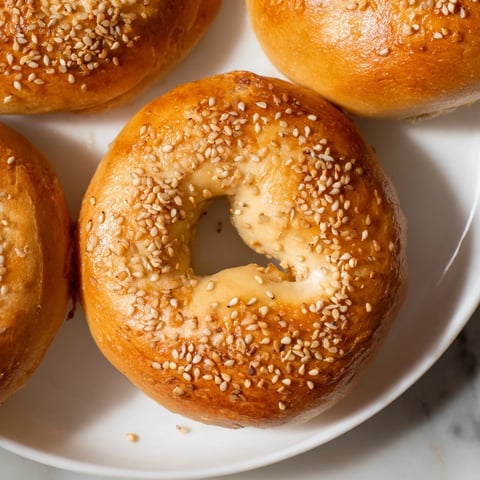 Steaming, golden-brown homemade budget bagels, perfect for a cozy breakfast with a smear of cream cheese.