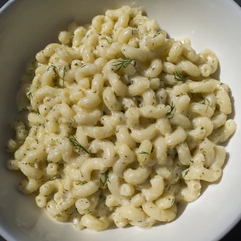 A close-up of creamy Pickle Mac and Cheese, with visible dill pickle pieces, ready to serve.