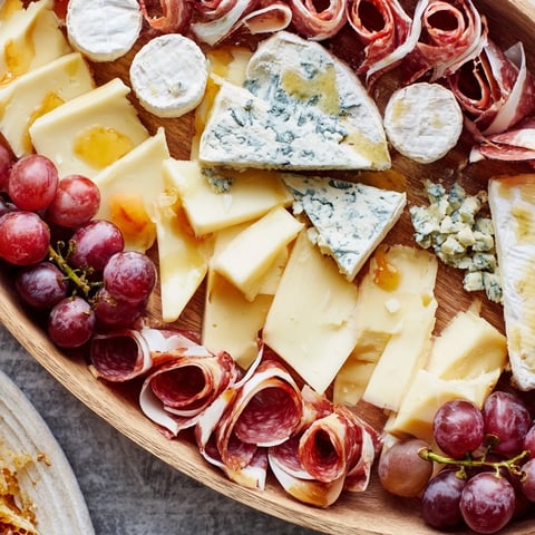 Elegant Gilded Edge cheese and charcuterie board overflowing with cheeses, meats, fruits, and nuts for entertaining.