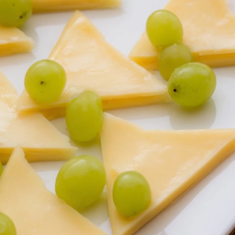 Festive The Tannenbaum Border cheese board with green grape "trees," perfect for holiday entertaining.
