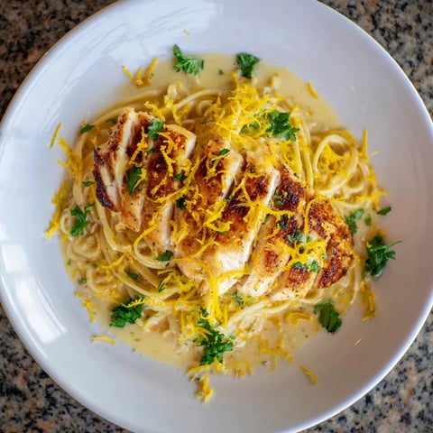 Golden-crusted lemon brûlée chicken atop creamy pasta, shown in this delicious recipe photo.