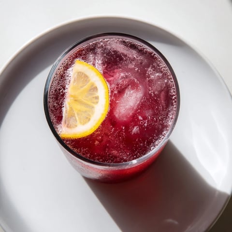 A vibrant Sleepy Girl Mocktail, a pink, effervescent drink, garnished with a lemon wheel for bedtime.