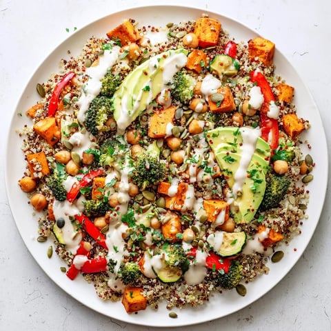 Steaming quinoa Buddha bowl with colorful roasted vegetables, topped with creamy tahini dressing, delicious.