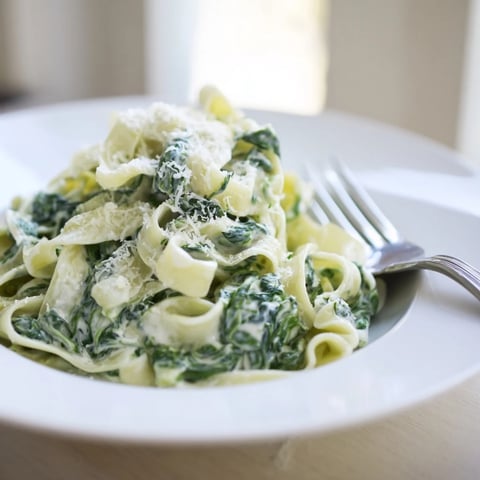 Creamy Spinach Garlic Noodles tossed in a rich, garlicky sauce with wilted baby spinach and Parmesan, served in a white bowl.