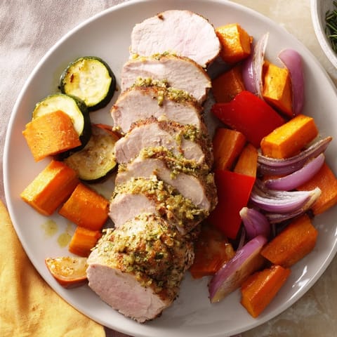 A close-up of a perfectly cooked roasted garlic pork tenderloin with tender, delicious vegetables for dinner.