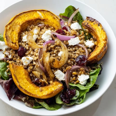 Golden, sweet maple-roasted acorn squash crowns this Farro & Mustard Green Salad, ready to enjoy.