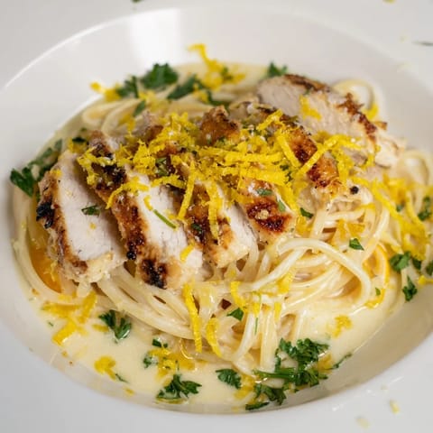 Thinly sliced lemon brûlée chicken complements the saucy pasta in this inviting recipe image.