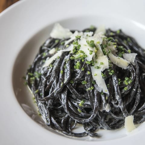 A beautiful swirl of dramatic squid ink pasta coated in a luxurious, creamy sauce with Parmesan.