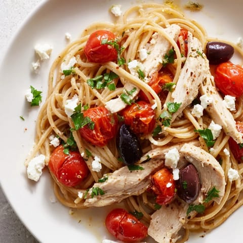 Fresh parsley and Kalamata olives garnish this vibrant Greek Chicken Spaghetti, ready to serve for a family dinner.