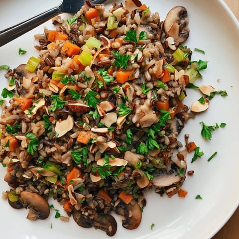 Fluffy wild rice and golden brown mushrooms glistening with herbs in this simple pilaf recipe, served warm alongside roasted chicken or as a standalone vegetarian main.