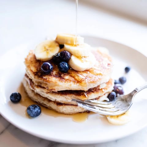 Fluffy Protein Power Pancakes cooking on a griddle, steam rising from their golden-brown surfaces in a sunlit kitchen.  