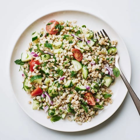 A close-up of the barley and herb salad with glistening lemon vinaigrette, diced cucumber, and cherry tomatoes ready for a light lunch.