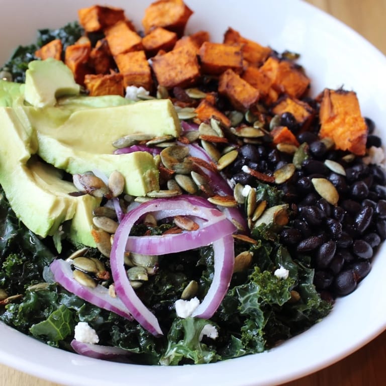 A healthy and vibrant massaged kale salad: visually appealing, with sweet potato and black beans for a balanced meal.