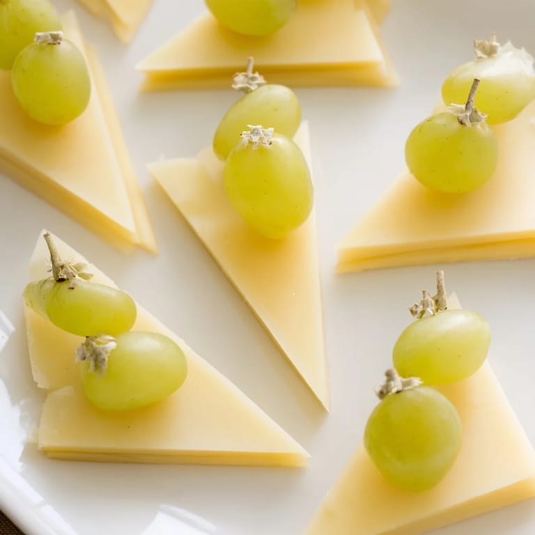 A stunning The Tannenbaum Border appetizer: triangular cheese "trees" bordering a vibrant platter of fruit.