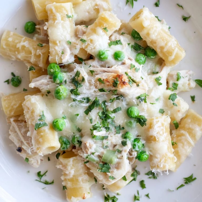 Golden, bubbly Slow Cooker Chicken Alfredo Pasta Bake, complete with tender pasta and melted cheese in a crockpot.
