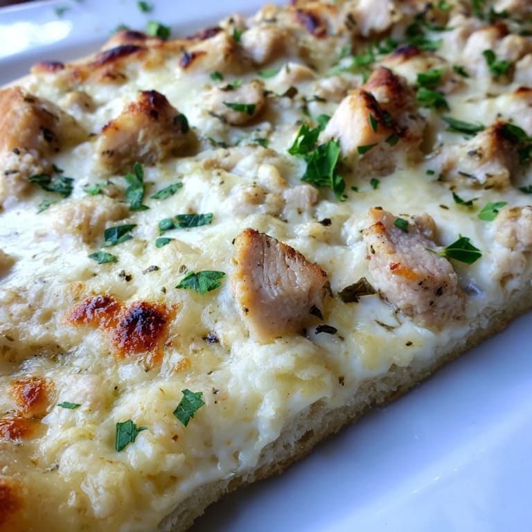 Sliced Chicken Alfredo Pizza on a wooden board, served with a fresh salad for dinner.
