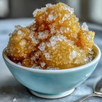 Vibrant limoncello sorbet in a chilled glass, garnished with fresh mint and lemon zest for a bright summer dessert.