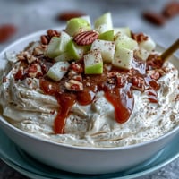 Creamy caramel apple cheesecake snack dip topped with fresh apples and nuts.